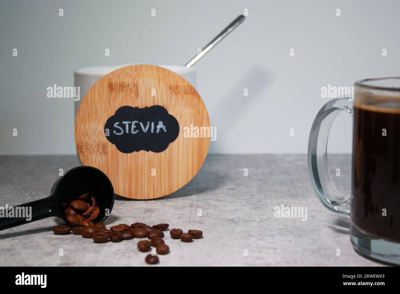 Una ciotola con dolcificante per la stevia e un bicchiere di caffè nero, sfondo grigio Foto Stock