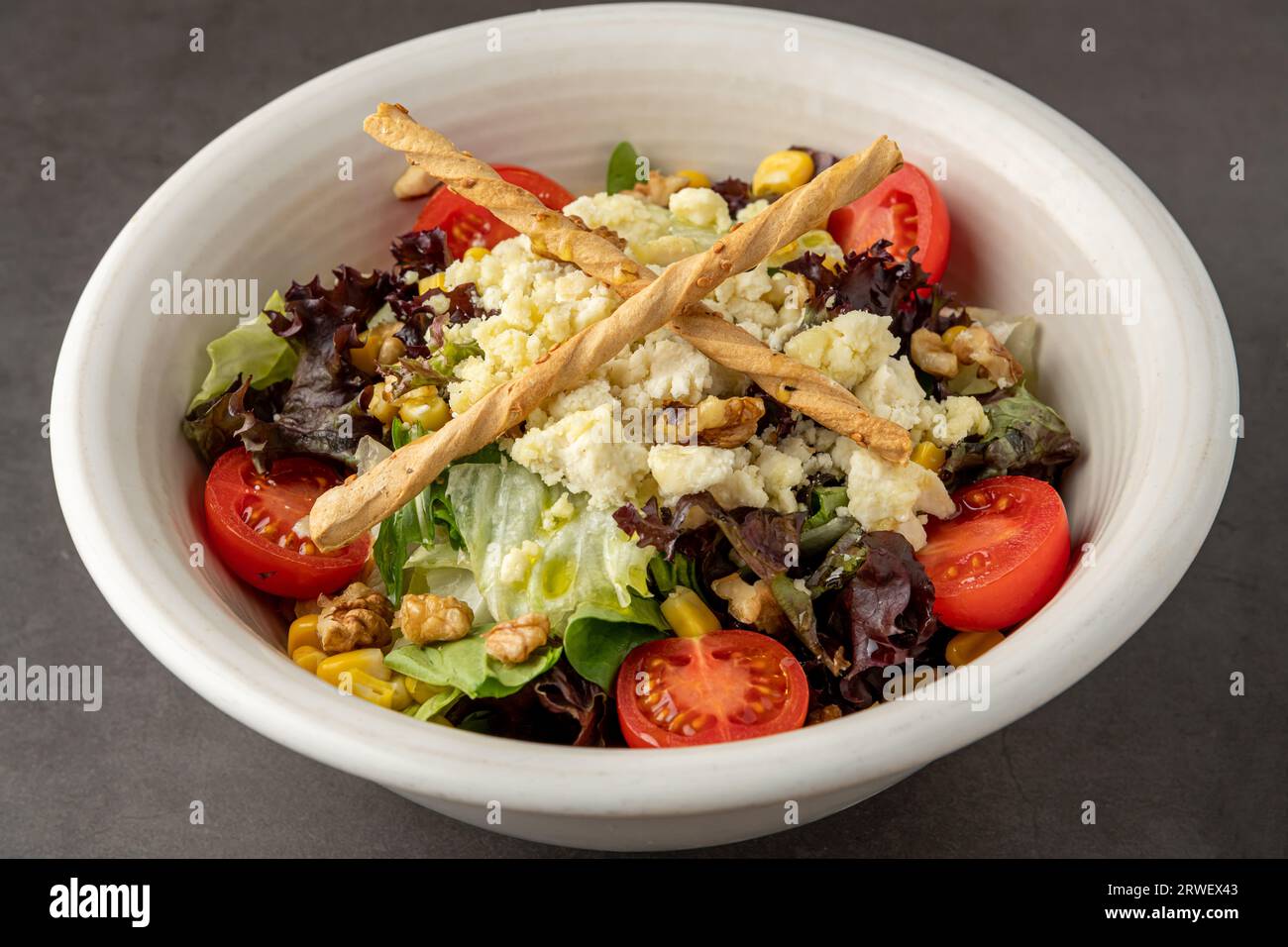 Insalata mediterranea con formaggio di capra in porcellana bianca su tavola di pietra Foto Stock