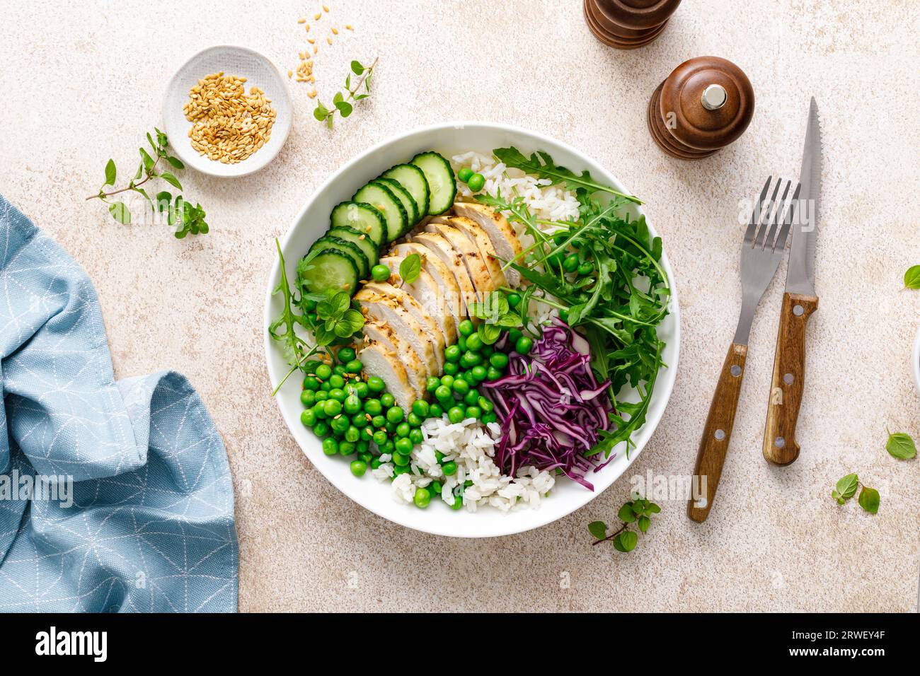 Piatto per pranzo con carne di pollo e riso con piselli verdi, cavolo rosso, cetriolo e insalata di rucola fresca Foto Stock