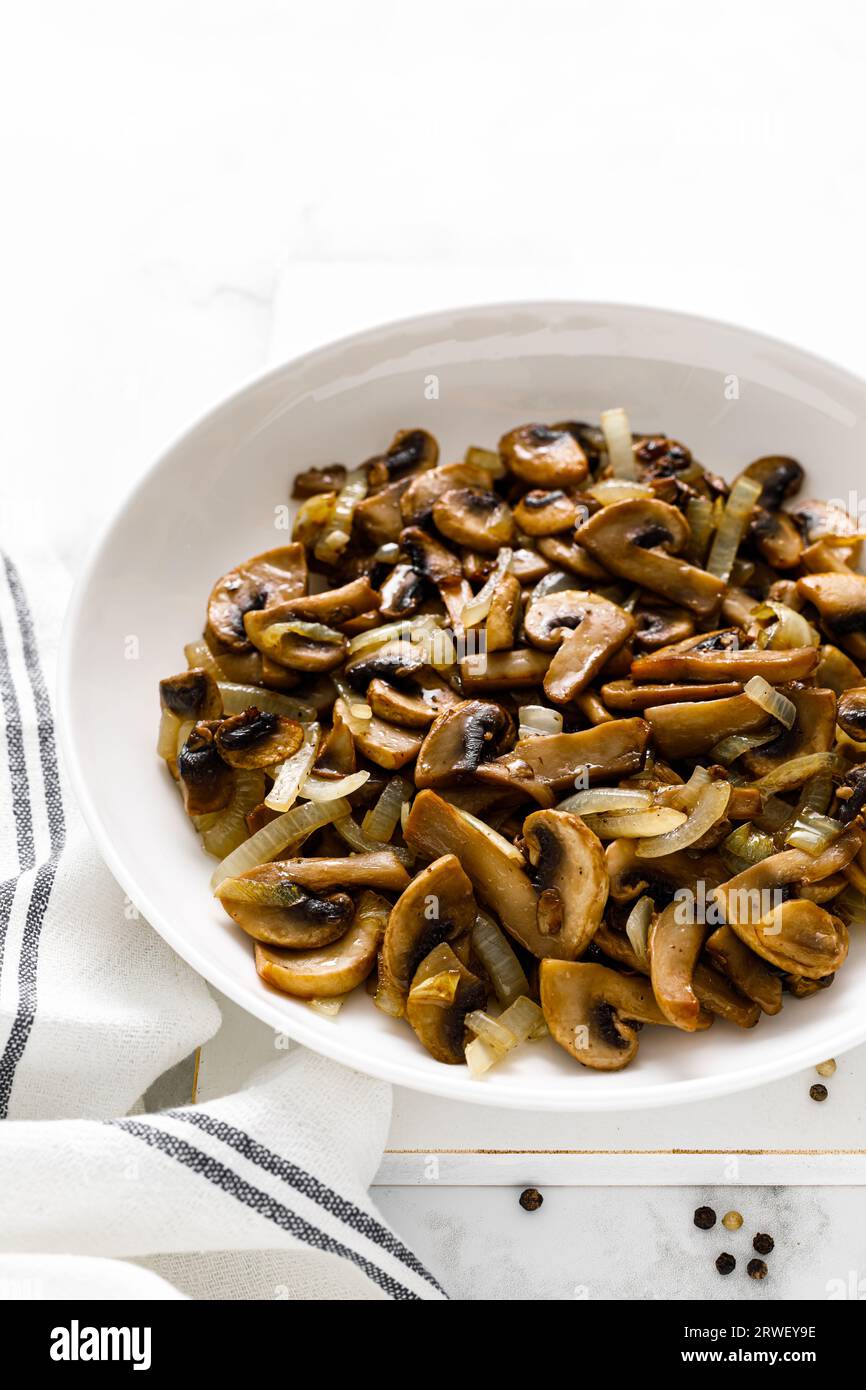 Funghi Champignon saltati con cipolla Foto Stock