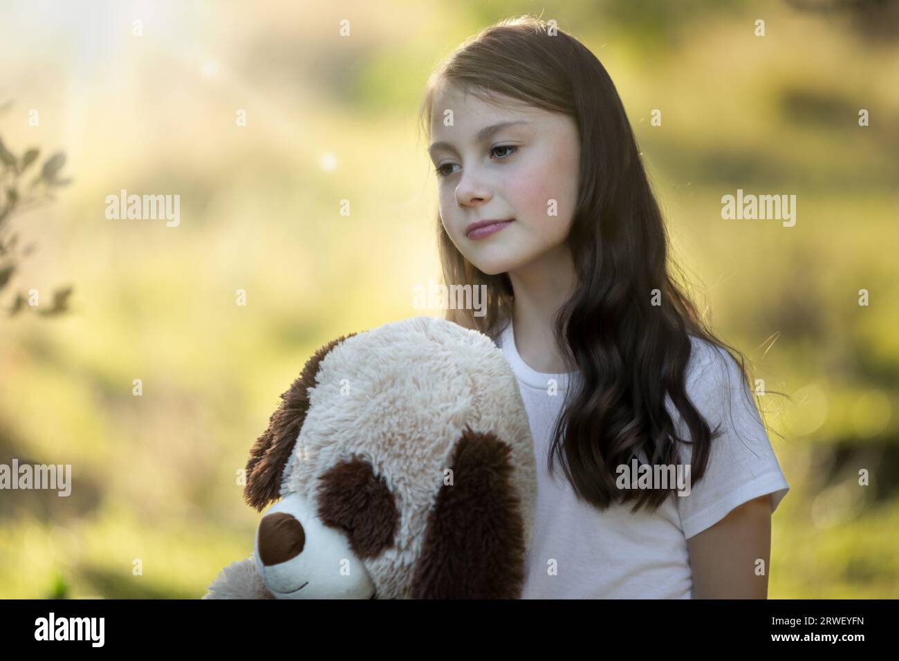 Primo piano di una giovane ragazza che tiene il suo orsacchiotto al tramonto Foto Stock