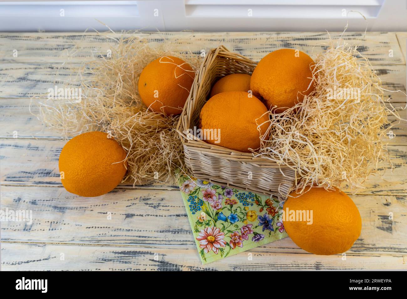 Natura morta con arance e cesto su un vecchio sfondo di legno luminoso Foto Stock