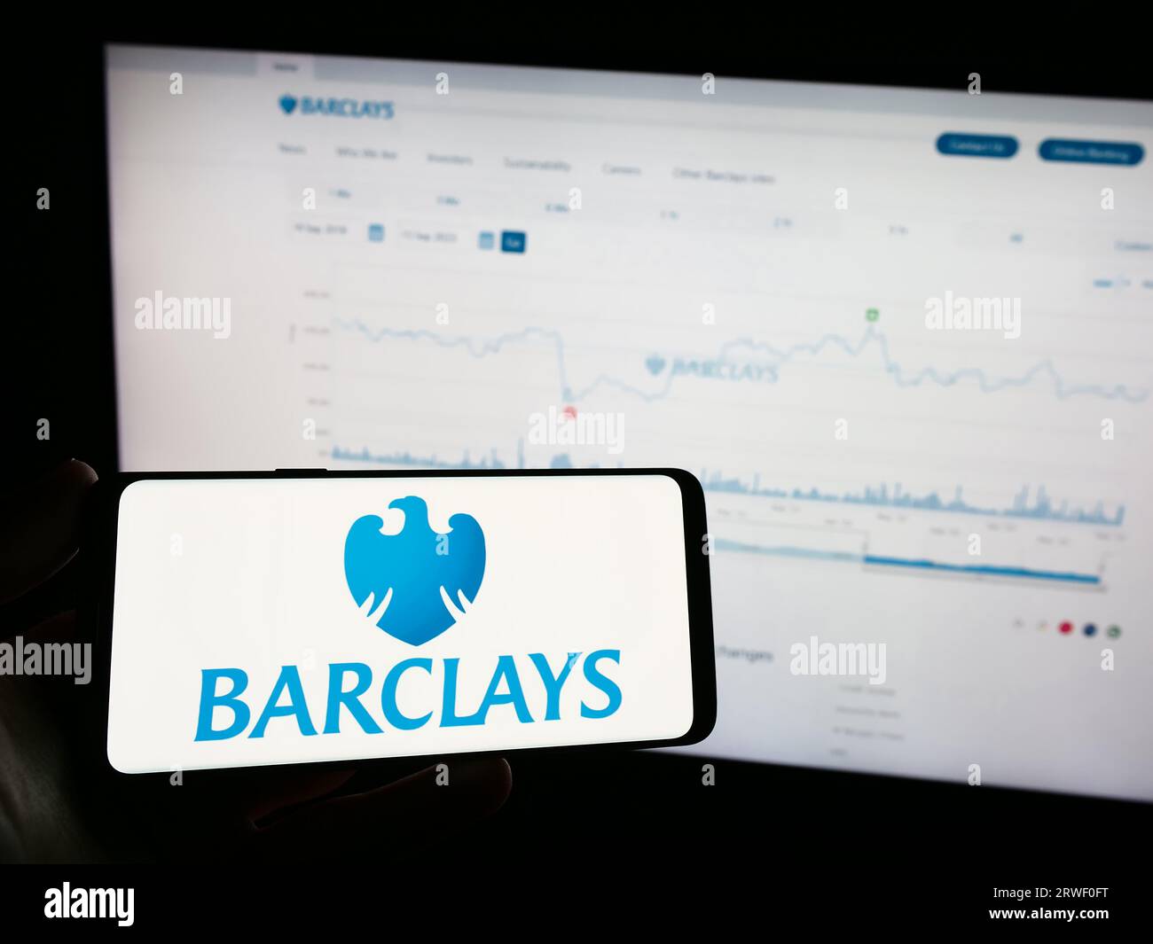 Persona che possiede un telefono cellulare con il logo della banca universale britannica Barclays plc sullo schermo di fronte alla pagina Web dell'azienda. Concentrarsi sul display del telefono. Foto Stock