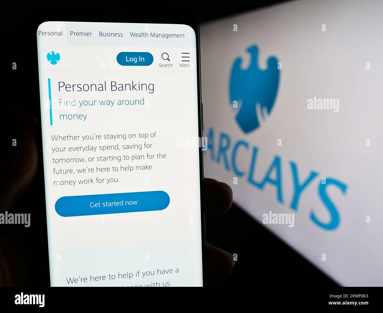 Persona che tiene uno smartphone con una pagina Web della banca universale britannica Barclays plc sullo schermo davanti al logo. Concentrarsi sul centro del display del telefono. Foto Stock