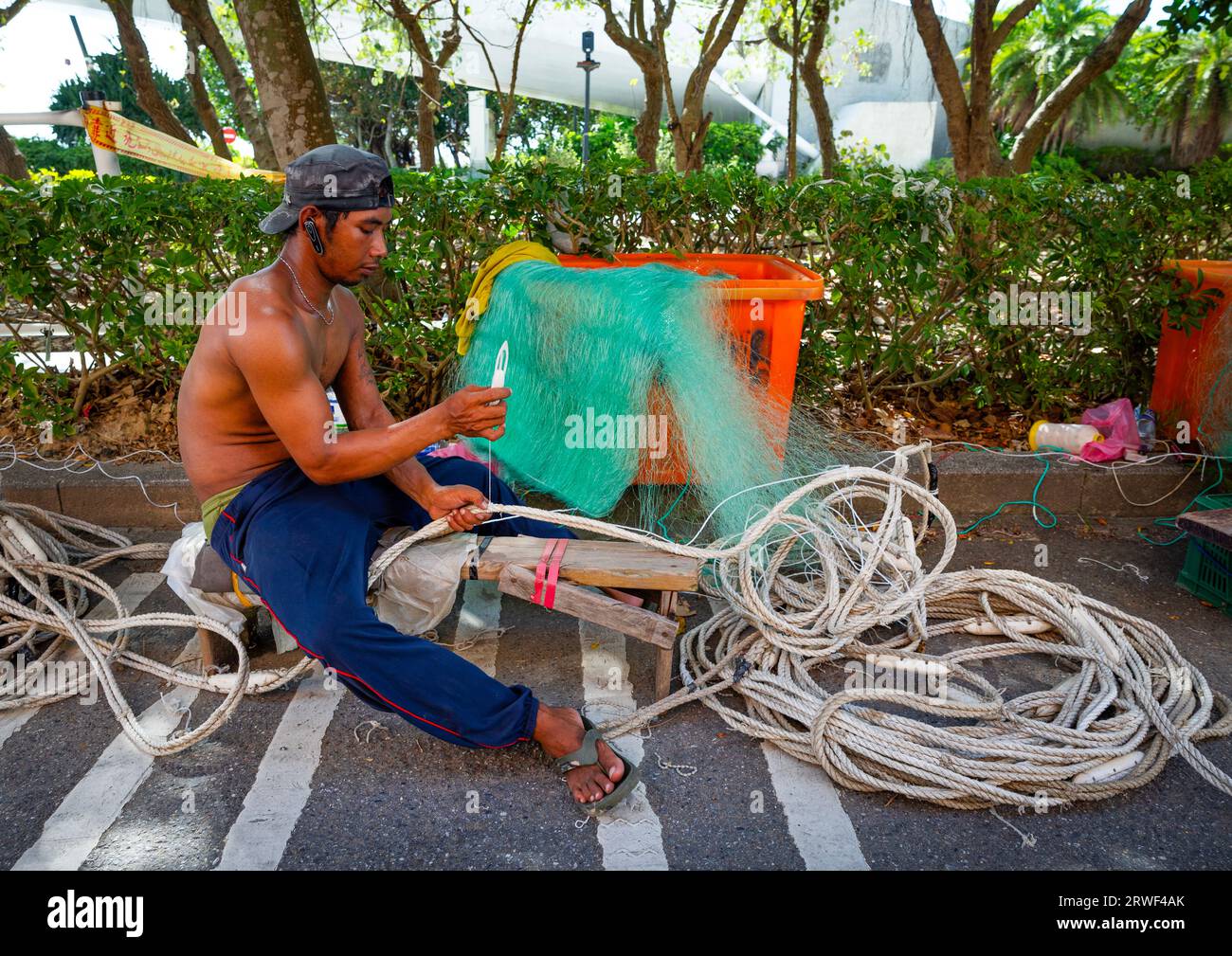 Uomo indonesiano che ripara una rete da pesca al Tamsui Fisherman Wharf, New Taipei, Tamsui, Taiwan Foto Stock