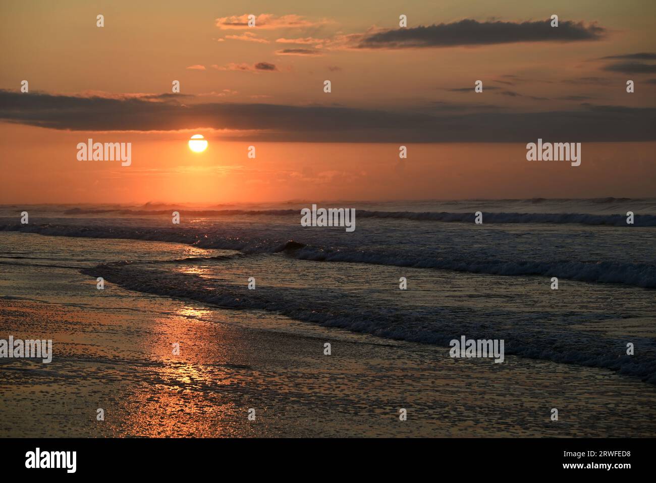 Il sole sorge all'orizzonte sull'Oceano Atlantico presso l'Hammocks Beach State Park nel North Carolina. Foto Stock