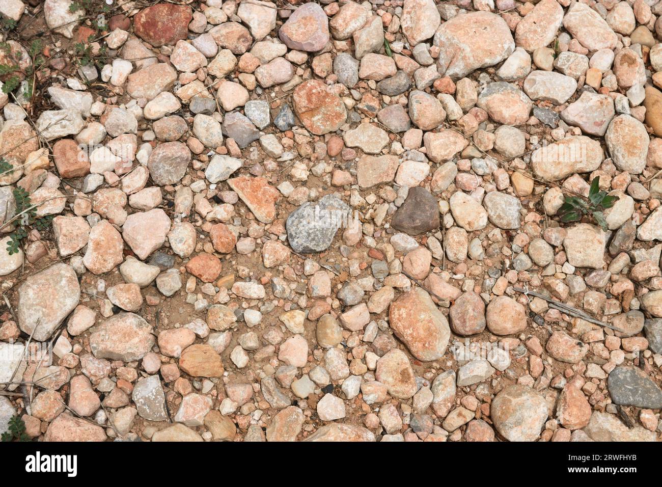 Immagine di alcune pietre e ghiaia che formano il terreno di una strada rurale che funge da sfondo per temi rustici Foto Stock