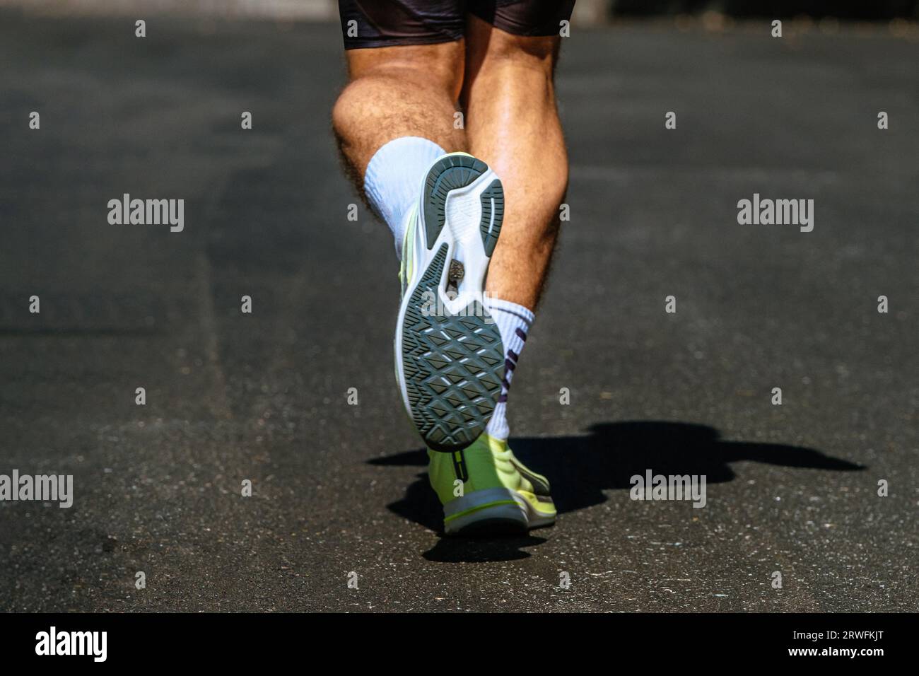 scarpa da running e gambe per primo piano, runner maschile su fondo dark road, gara di maratona Foto Stock