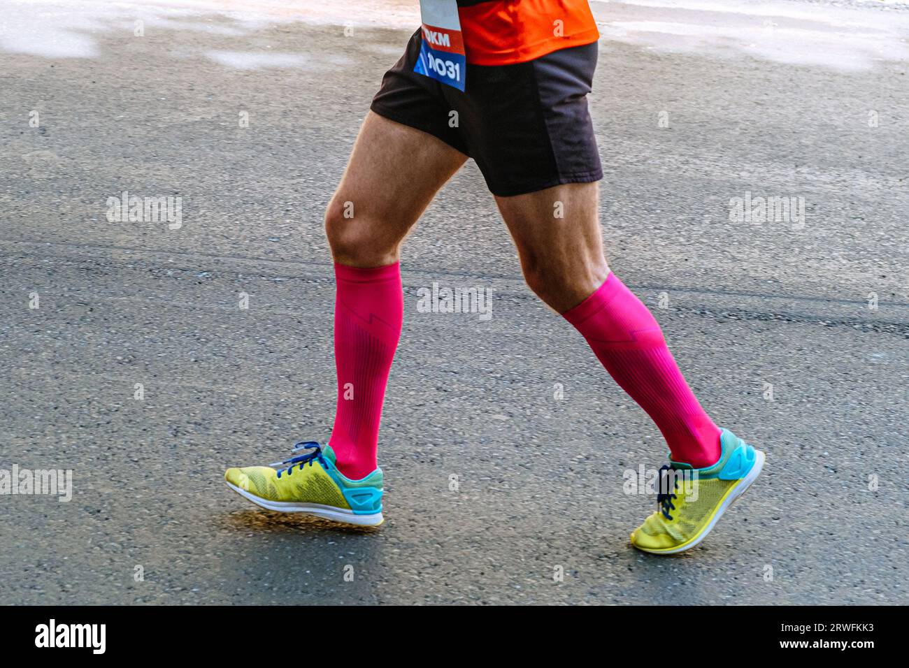 corridore maschile con gambe ravvicinate in calze a compressione rosa che corre su asfalto gara di maratona su strada Foto Stock