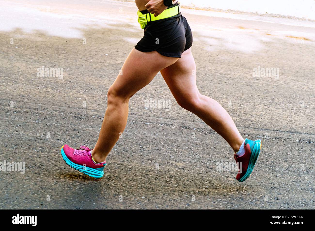 le gambe ravvicinate corridore femminile che corre su una maratona su strada asfaltata Foto Stock