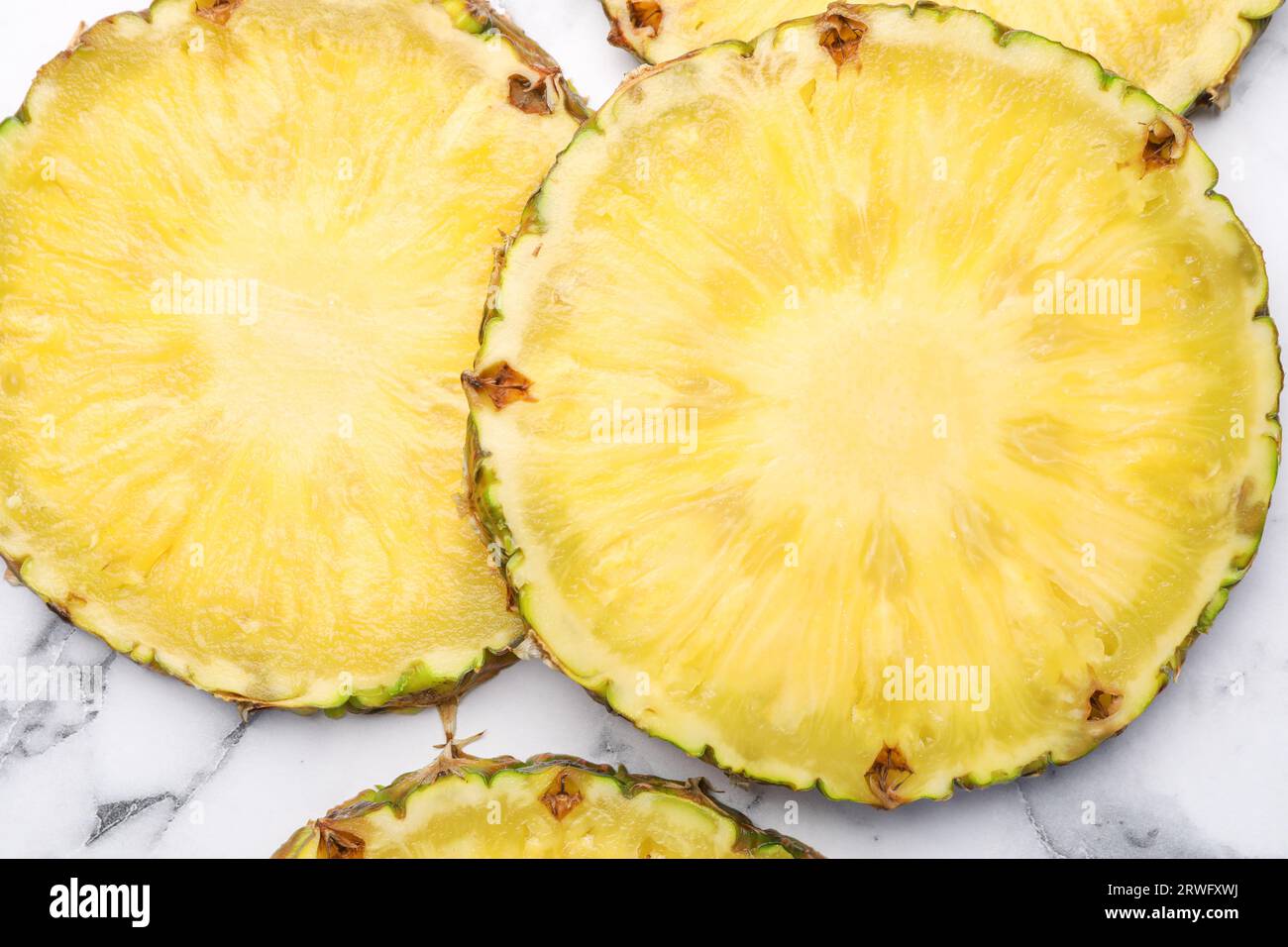 Fette di gustoso ananas maturo su un tavolo in marmo bianco, piatto Foto Stock