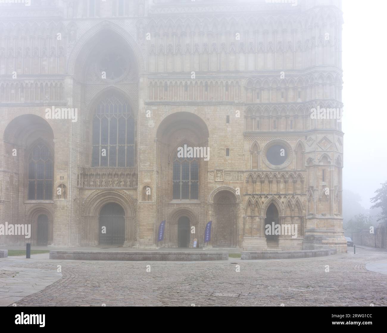 West End e ingresso principale alla cattedrale medievale costruita dai normanni a Lincoln, Inghilterra, in una mattina nebbiosa. Foto Stock