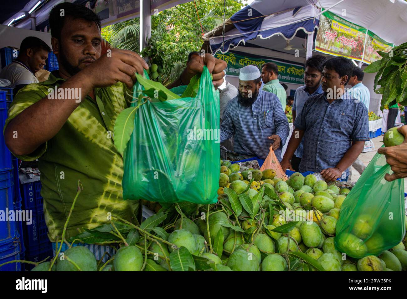 Persone che acquistano mango da una bancarella del National Fruit Festival organizzato dal ministero dell'agricoltura, Dacca, Bangladesh. Foto Stock