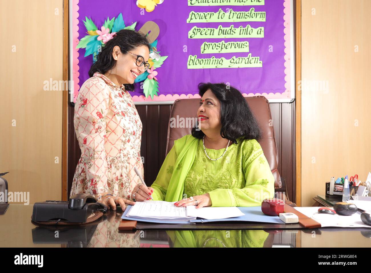 Preside della scuola Mam che controlla alcuni documenti importanti in un file con il suo assistente personale, discussione, firma dei documenti, progressi nell'istruzione Foto Stock