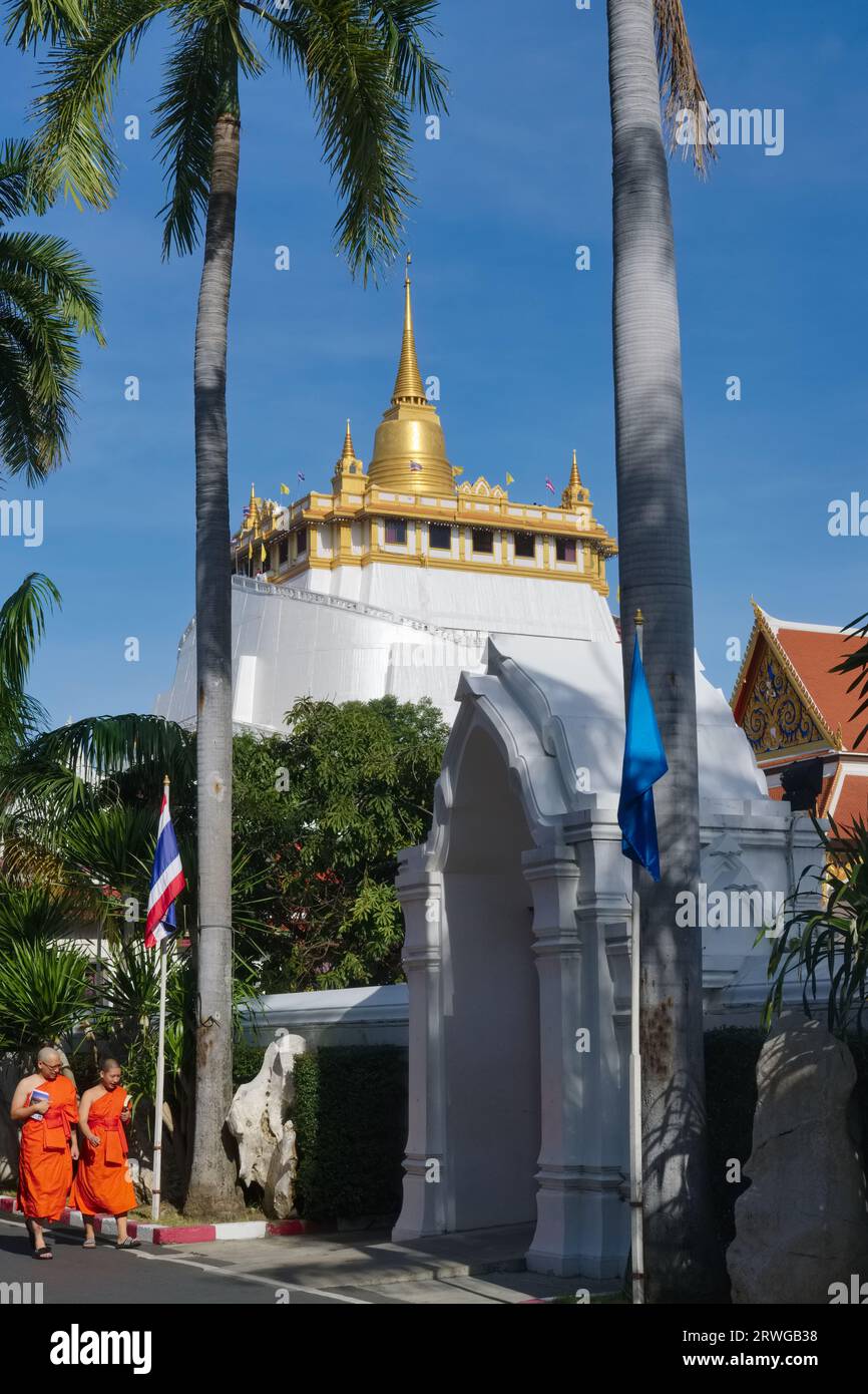Due monaci buddisti che camminano negli estesi terreni di Wat Saket, Bangkok, Thailandia, con l'iconico Monte d'Oro (Phukhao Thong) sullo sfondo Foto Stock
