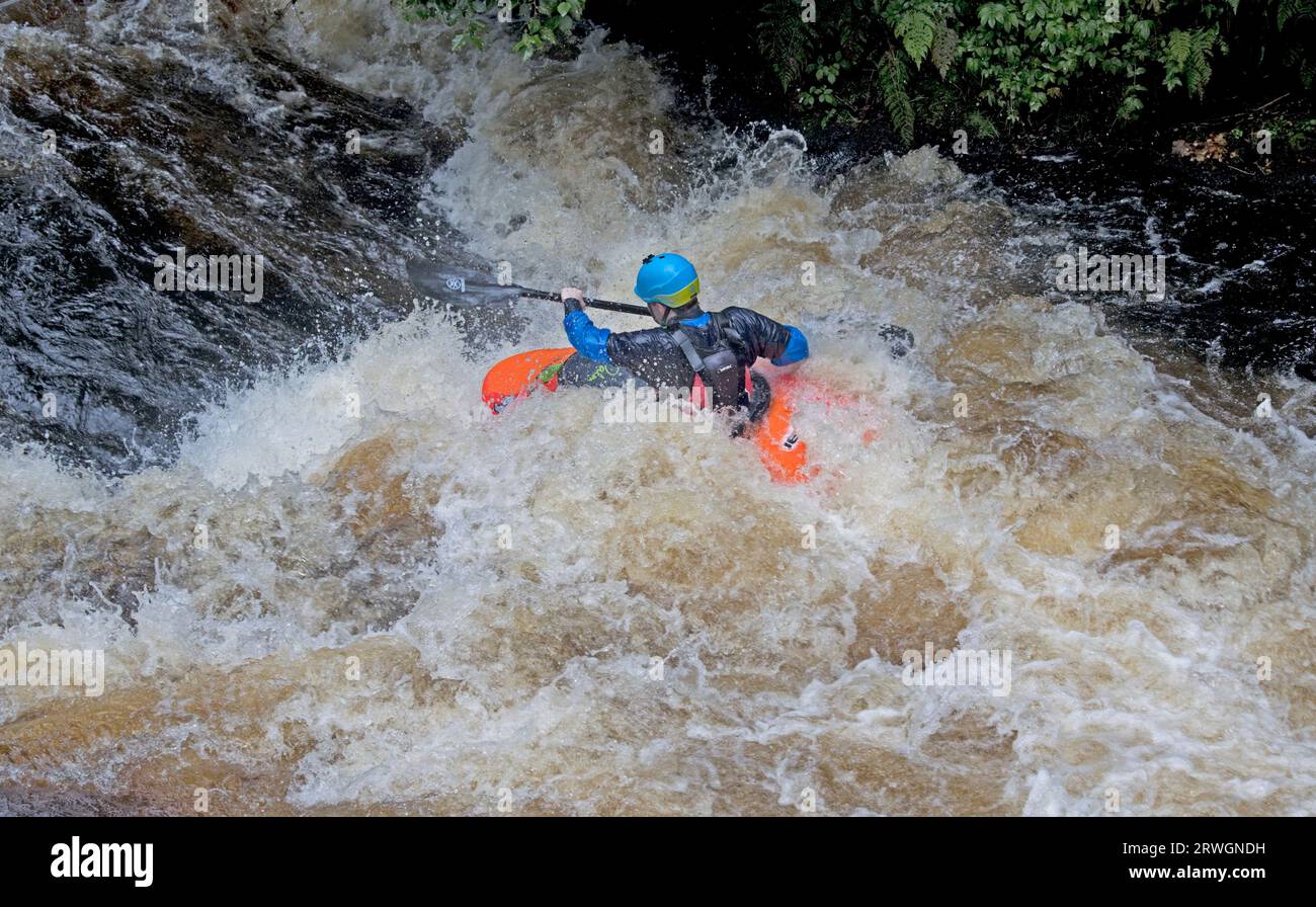 Canoa da slalom arancione che cavalca le rapide canoa da slalom Whitewater nel fiume Tryweryn presso il National Whitewater Centre vicino a Bala nel Galles del Nord Foto Stock