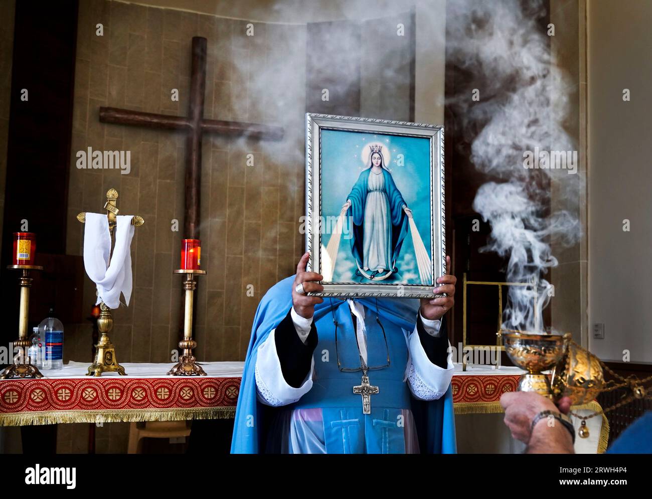L'Arcivescovo maronita Hanna Rahme di Deir al-Ahmar conserva un'immagine della Vergine Maria durante un servizio presso la chiesa di San Giovanni Battista nel villaggio di Tall Safiya nella piana di Beeka, Libano Foto Stock