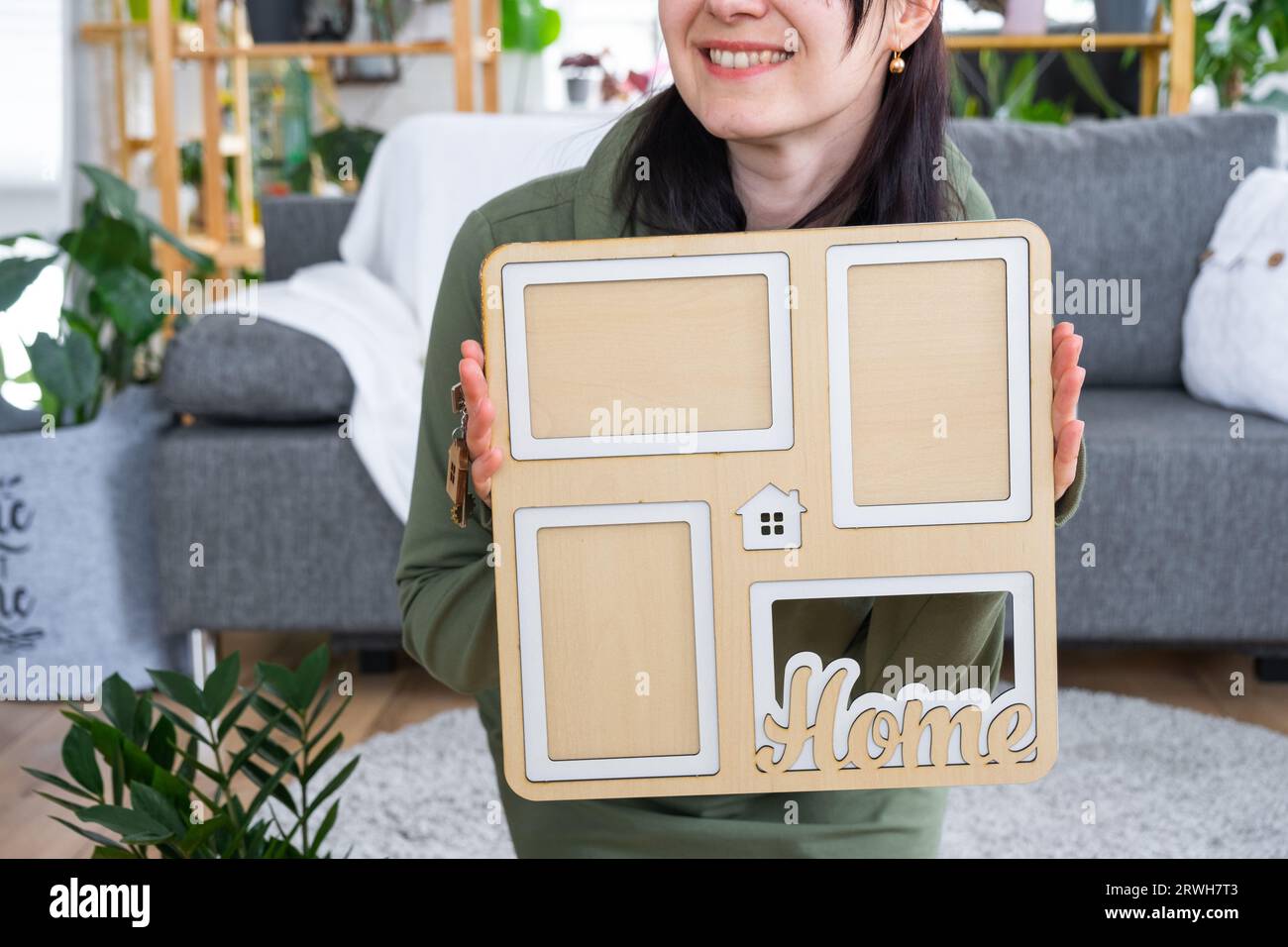 Happy Woman in casa tiene in mano cornice fotografica con modello di figura a casa e chiave all'interno. Progetto casa dei sogni, acquisto di immobili, assicurazione Foto Stock