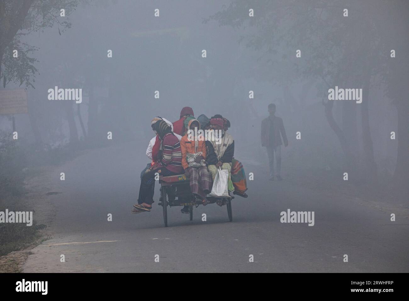 Persone a basso reddito che viaggiano su un pulmino in risciò in una mattina d'inverno a Savar a Dacca, Bangladesh. Foto Stock