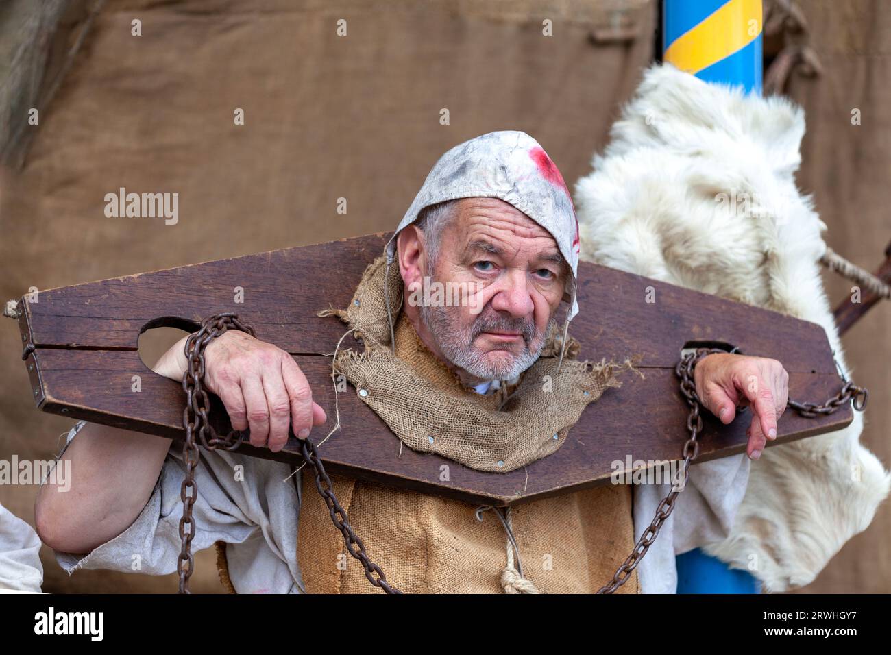 Saint Renan, Francia - 16 luglio 2023: Uomo in abiti medievali incatenato alla gogna durante il Saint Renan Medieval Festival. Foto Stock