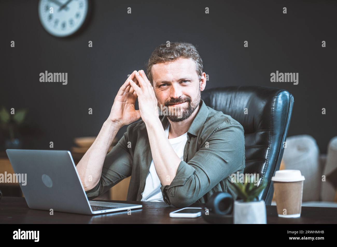 Un uomo d'affari sicuro di sé, che trasuda professionalità e leadership, prende decisioni fondamentali sulla base di meticolosi dati di analisi computerizzata. Con le mani piegate con un gesto contemplativo, guarda direttamente alla fotocamera. Foto di alta qualità Foto Stock