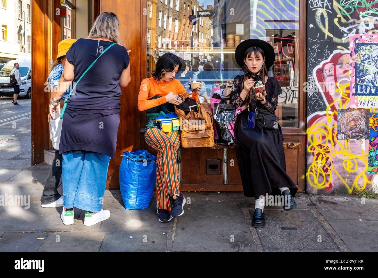 Turisti asiatici che mangiano gelato, Brick Lane, Londra, Regno Unito. Foto Stock