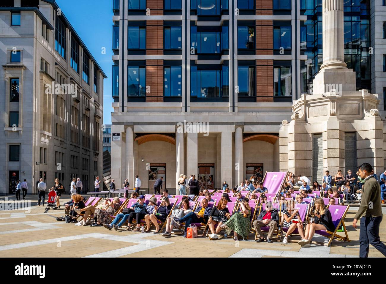 Persone sedute su sedie a sdraio che si godono il sole, Paternoster Square, la città di Londra, Londra, Regno Unito. Foto Stock