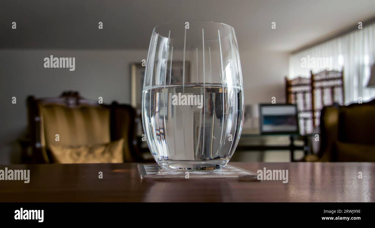 Vetro mezzo pieno di acqua isolato sfondo sfocato sfocato Foto Stock
