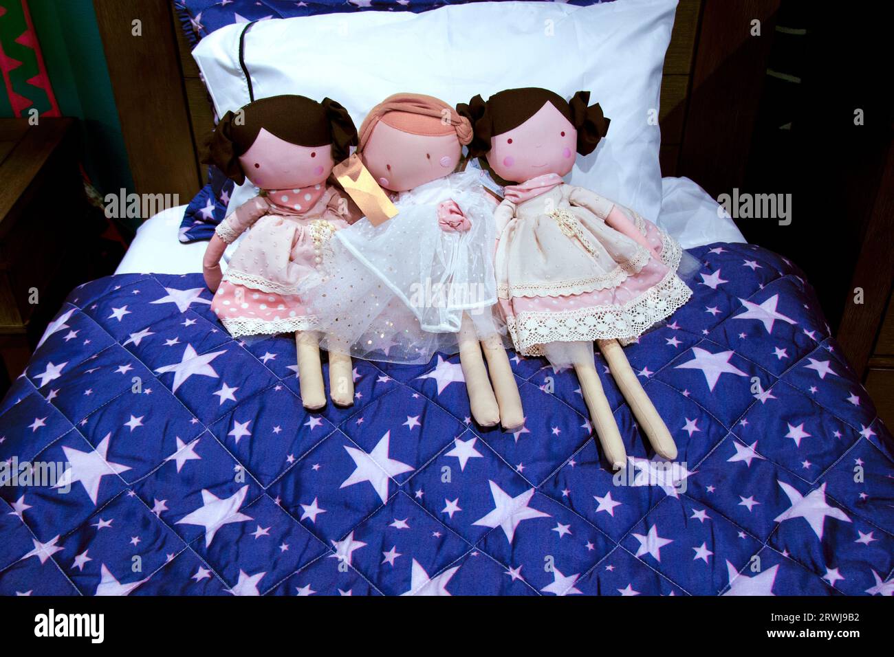 Tre bambole di stoffa con etichette su un letto Foto Stock