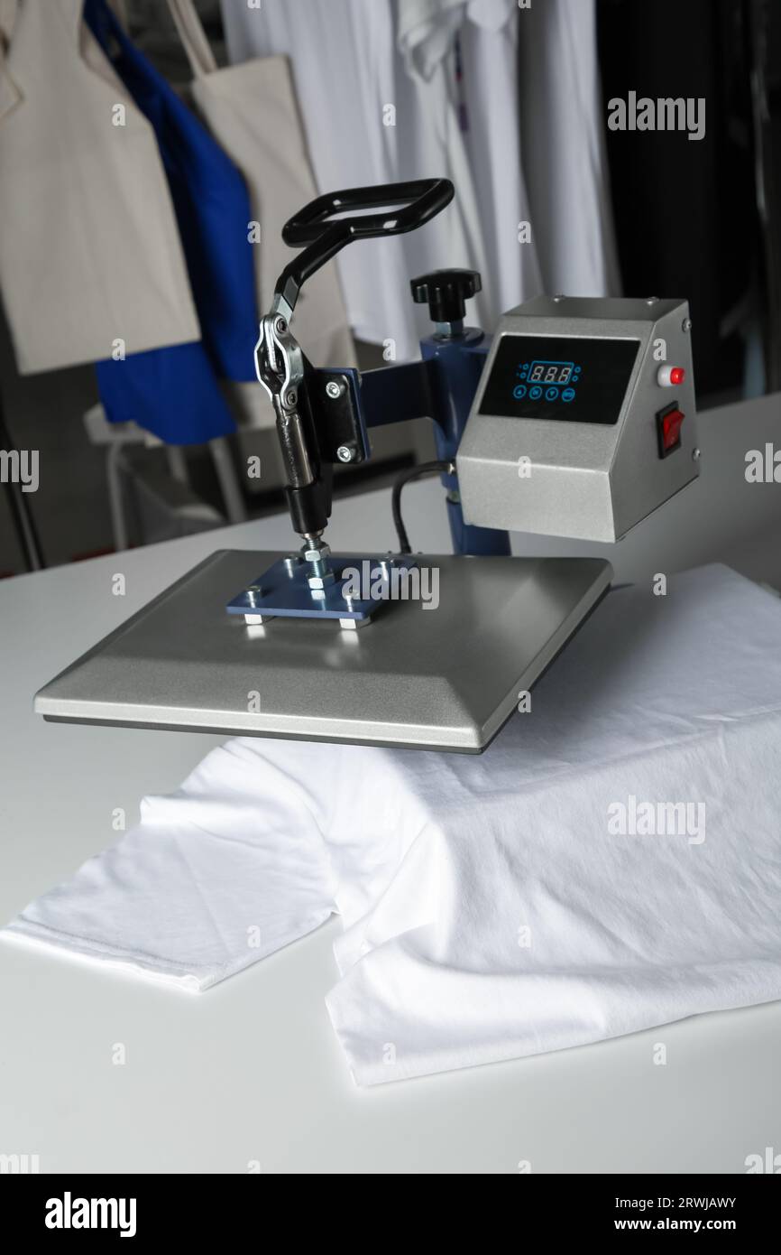 Stampa logo. Pressa a caldo con t-shirt su tavolo bianco Foto Stock