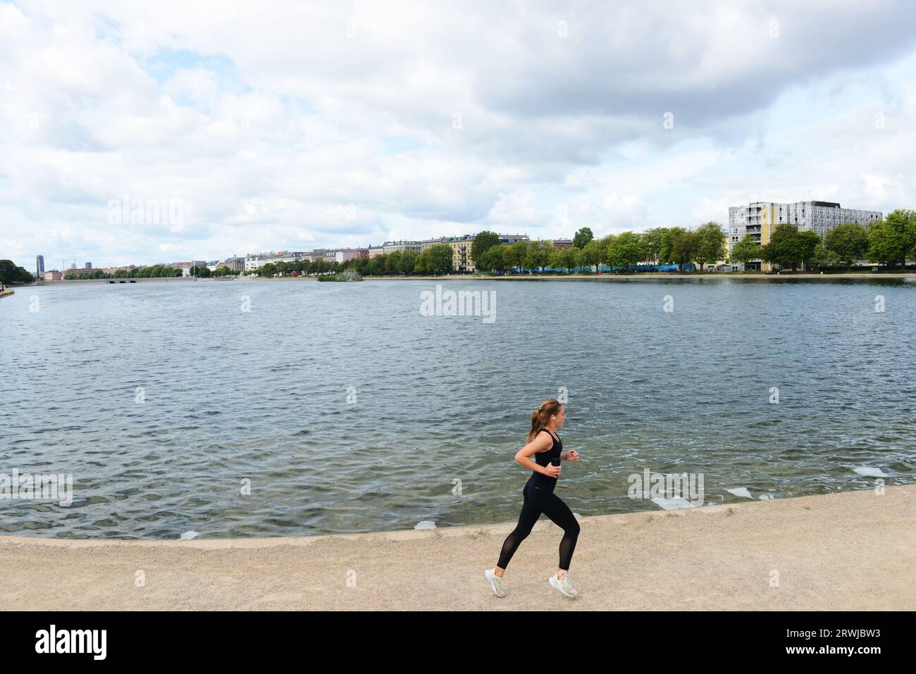 Una donna che fa jogging sul lago Sortedam a Copenaghen, Danimarca. Foto Stock