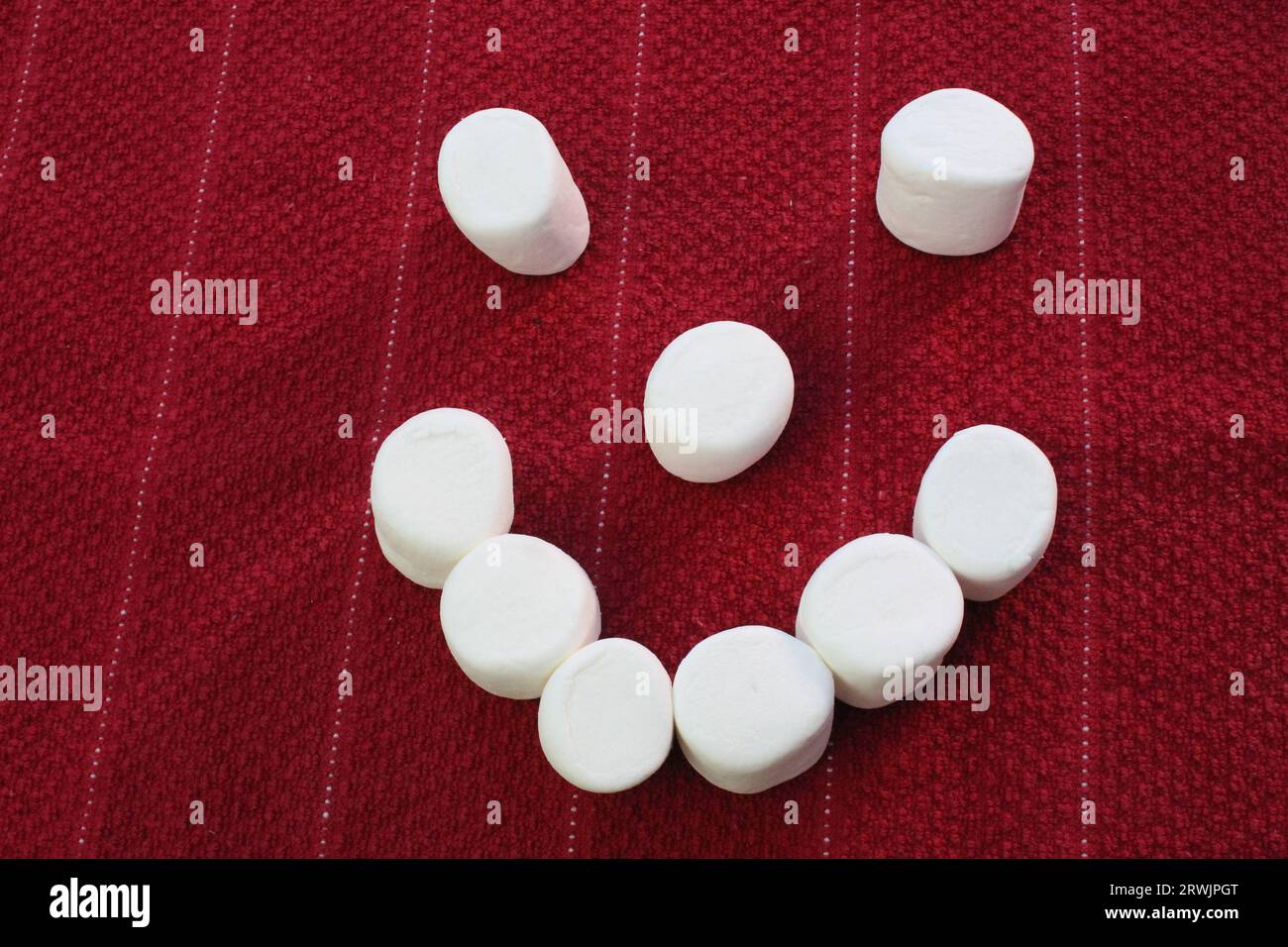 Faccia sorridente Marshmallow, faccia felice su sfondo rosso Foto Stock
