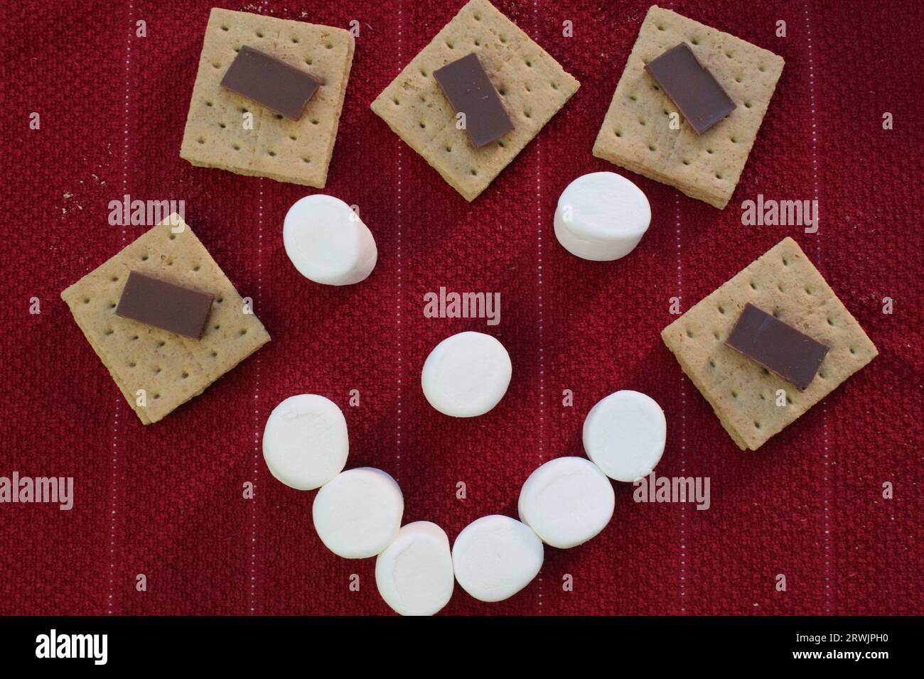 Smore Smiles Marshmallow Face, sorridi sullo sfondo rosso Foto Stock