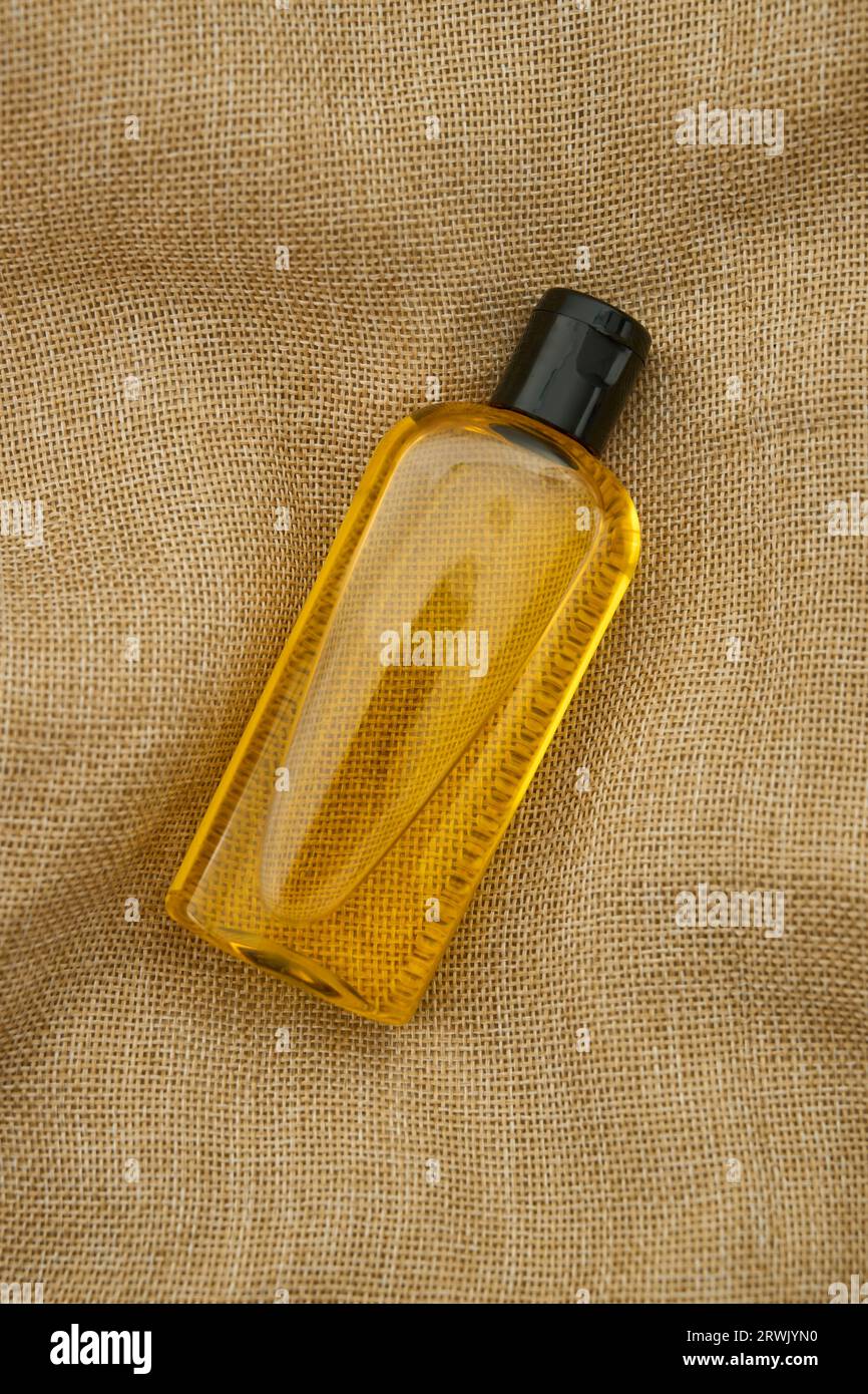 Una bottiglia d'olio jojoba con tappo nero su tessuto giallo, shot orizzontale, shot a livello degli occhi Foto Stock