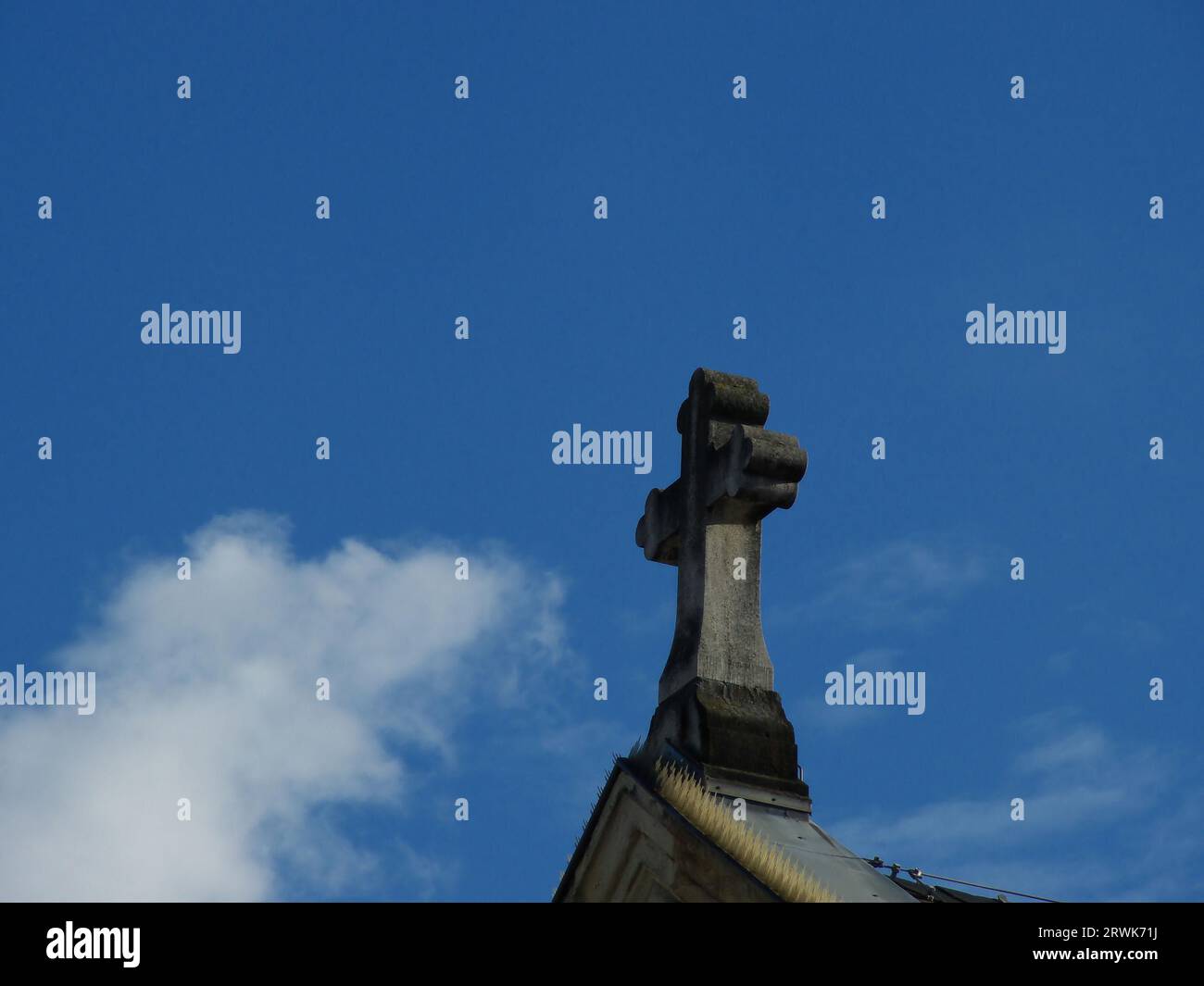 Croce di pietra sul tetto di una chiesa, sfondo cielo blu Foto Stock