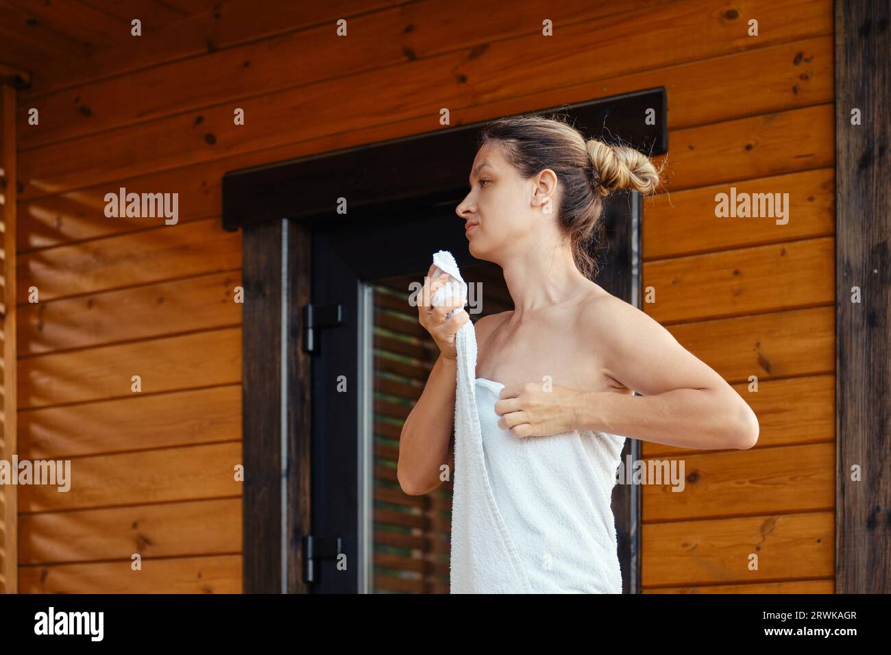 Una donna si avvolge in un asciugamano dopo aver lasciato la sauna Foto Stock