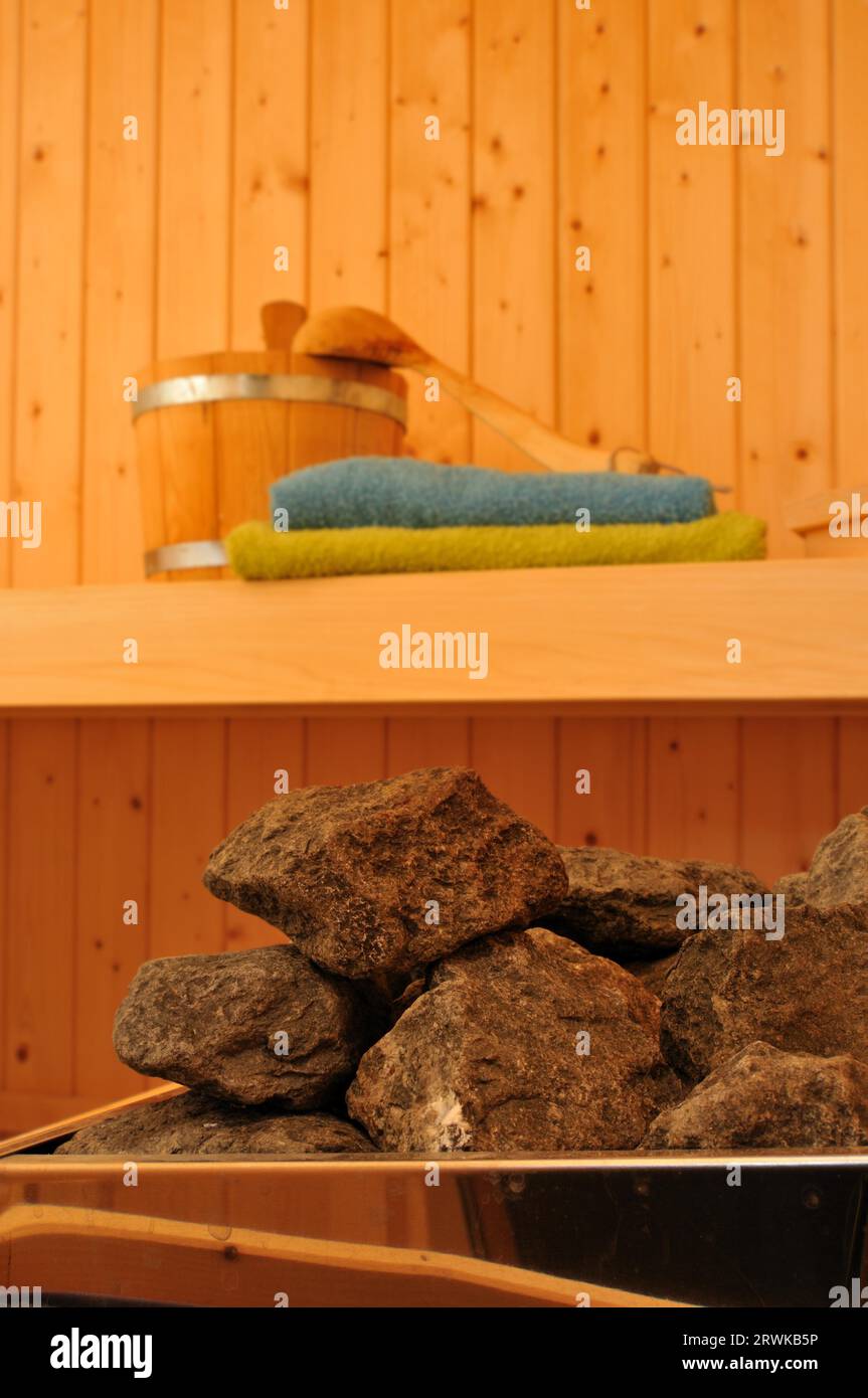 Vista su una sauna. In primo piano il riscaldamento della sauna e gli accessori per la sauna sullo sfondo Foto Stock
