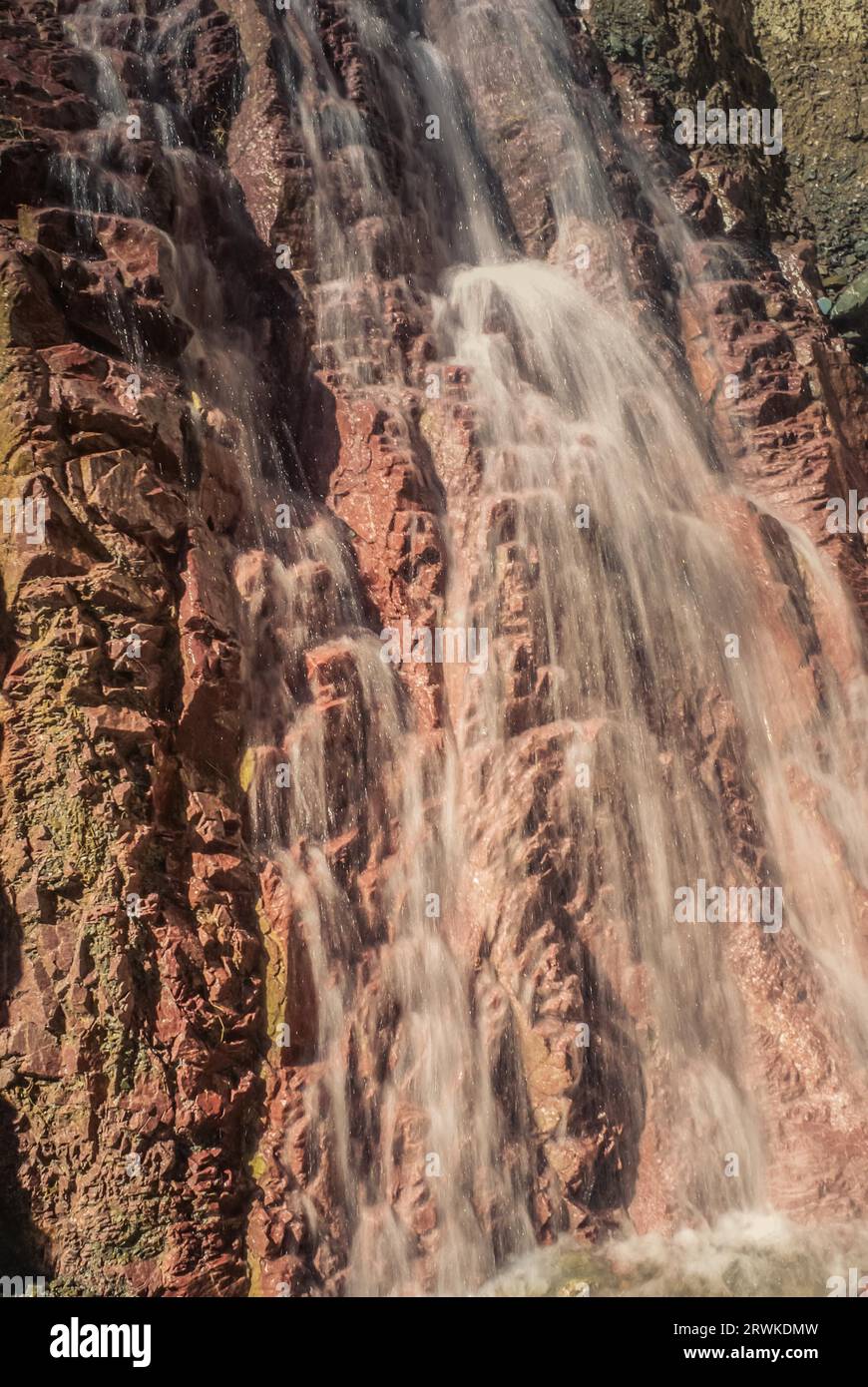 Foto di una cascata che cade su una parete rossa di roccia in Argentina Foto Stock