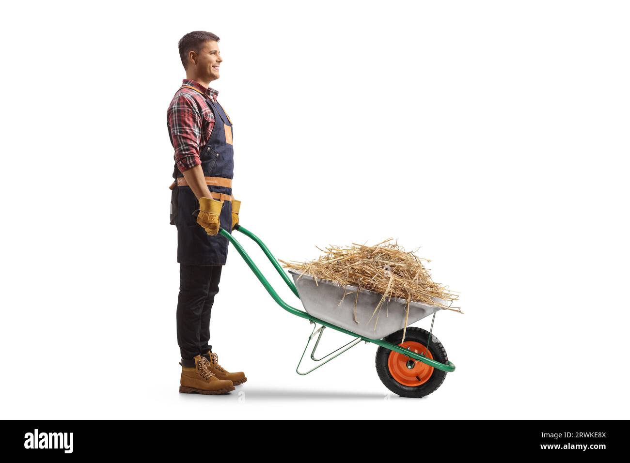 Immagine del profilo completo di un agricoltore con fieno in una carriola isolata su sfondo bianco Foto Stock