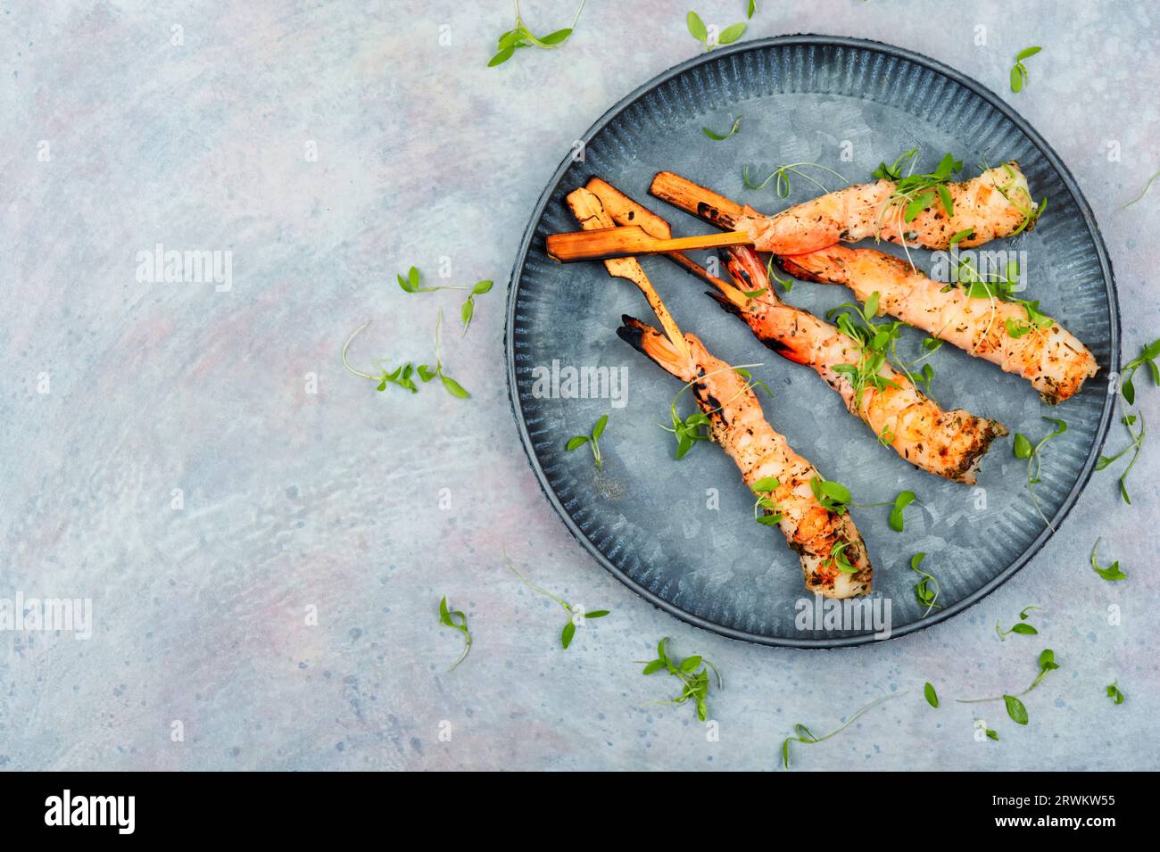 Gustoso barbecue di gamberi con erbe fritte su bastoncini di legno. Spiedini di gamberi. Spazio per il testo Foto Stock