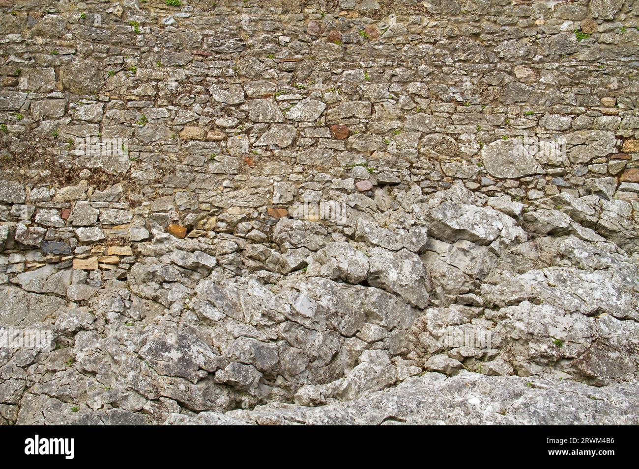 Muro medievale, costituito da pietre scavate grezze, costruito su roccia Foto Stock