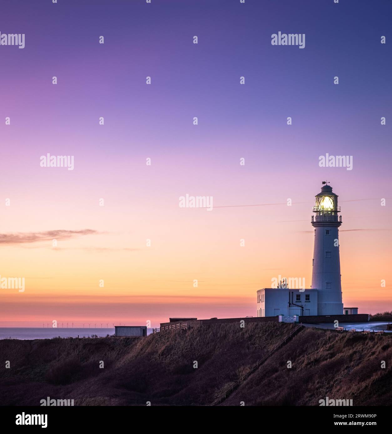 Faro Flamborough Head all'alba con cielo limpido e colore giallo arancio. La luce del faro è accesa Foto Stock