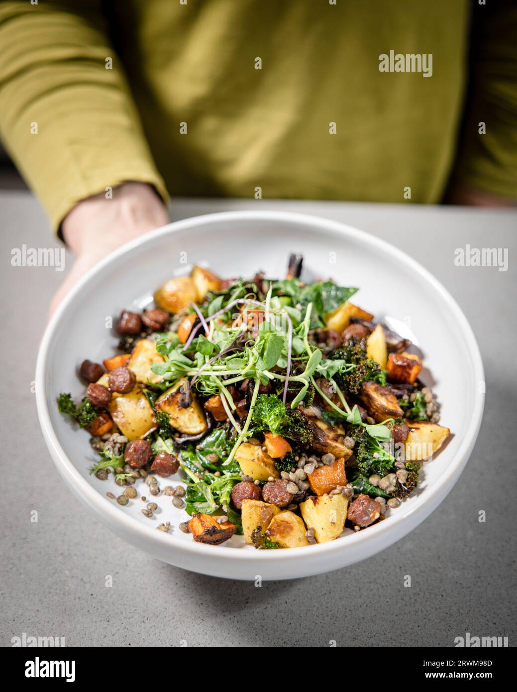 un piatto pieno di un'insalata vivace e nutriente, con un colorato mix di patate, carote, broccoli, germogli di piselli e lenticchie verdi. Il piatto Foto Stock