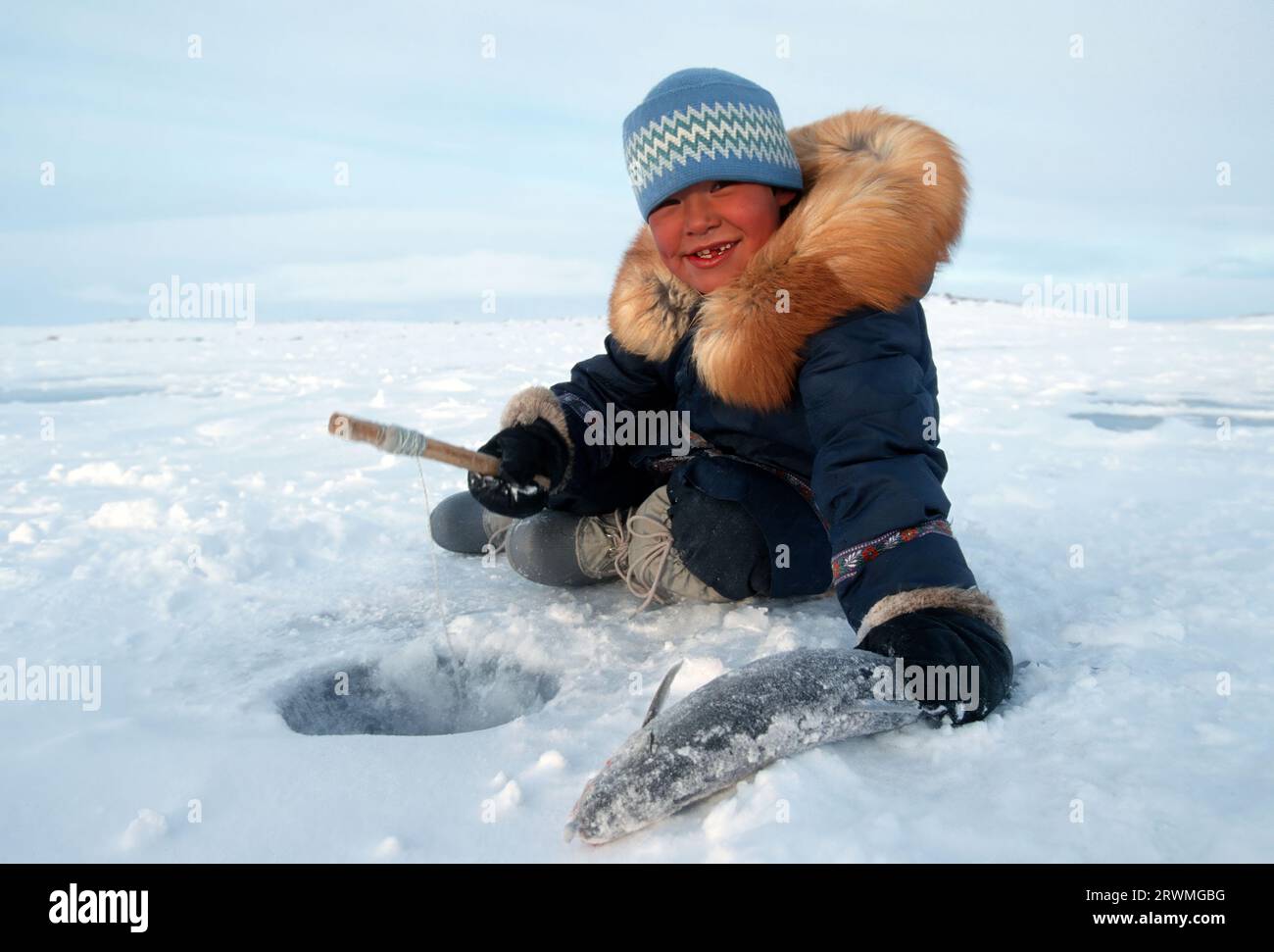 Kanada, CAN, Inuit Eskimosjunge fischt mit einer Angel durch ein Loch im Eis auf einem SEE a Nunavik, Provinz Quebec, Nord-Kanada | Inuit boy fishing through a hole on a Lake in Nunavik, Quebec Province, North-Canada Foto Stock