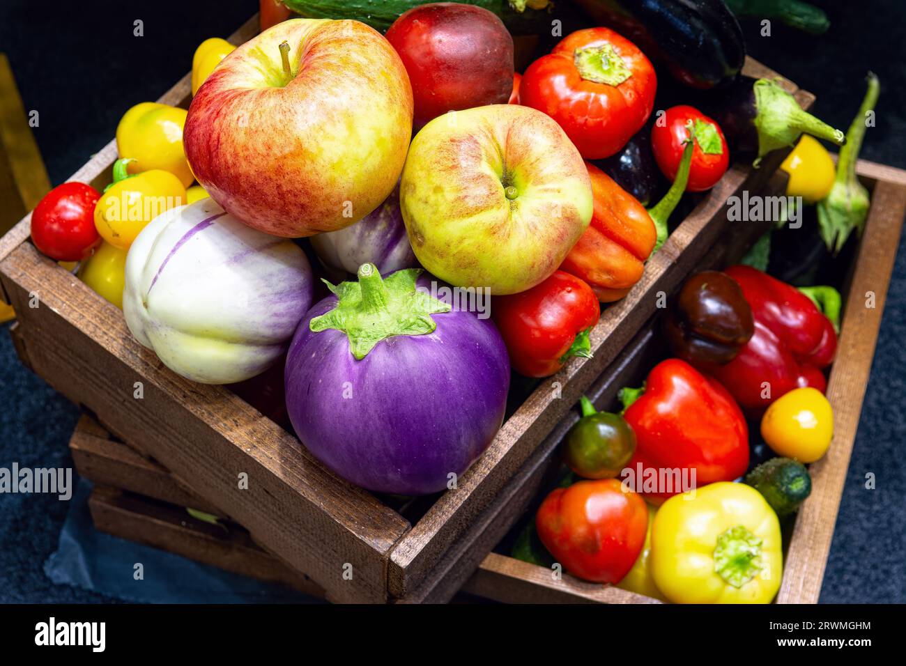 Vista dall'alto di vari tipi di frutta e verdura in scatole di legno. Mele mature, pomodori, peperoni, varie melanzane. Frutta e verdura fresca a partire dal proprio g Foto Stock