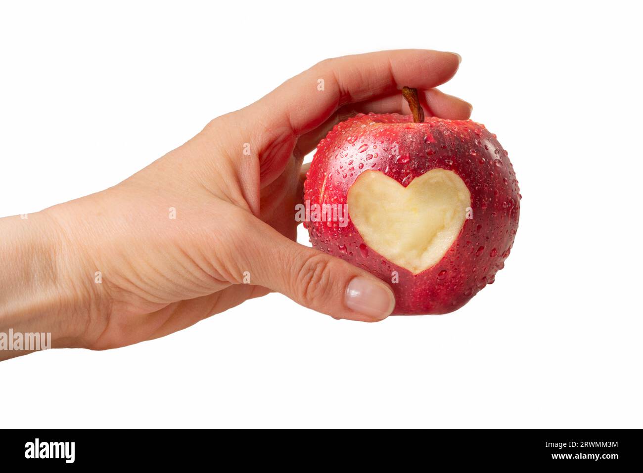 Mano femminile che tiene la mela rossa con il simbolo del cuore e gocce d'acqua isolate Foto Stock