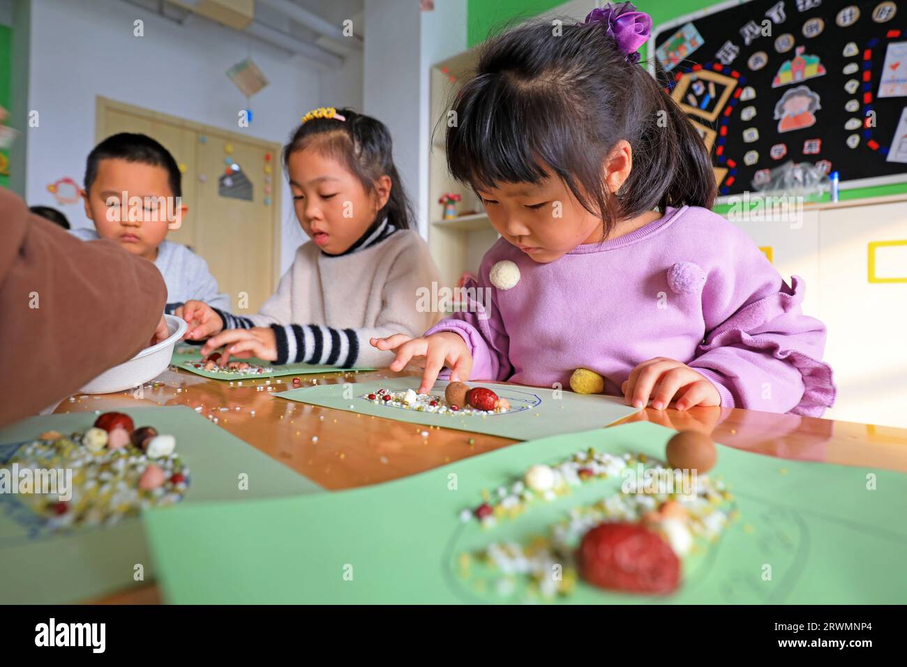 LUANNAN COUNTY, Cina - 7 gennaio 2022: I bambini dell'asilo fanno i compiti manuali del Laba Festival, Cina del Nord Foto Stock