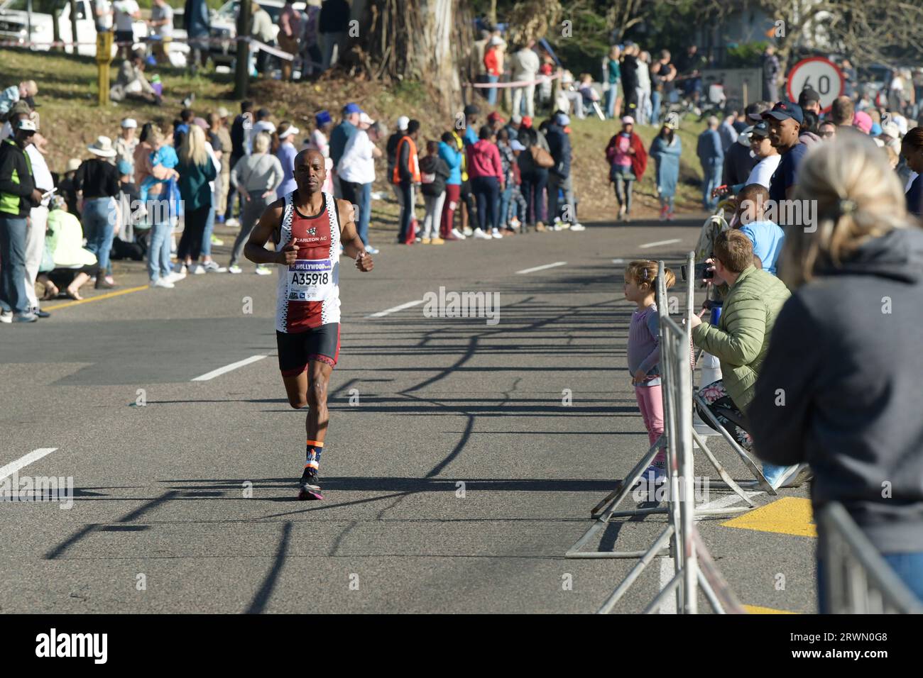 Persone che guardano Man Running, 96th Comrades Marathon 2023, Durban, Sud Africa, runner in gara di endurance, iconico evento internazionale di atletica, sport Foto Stock