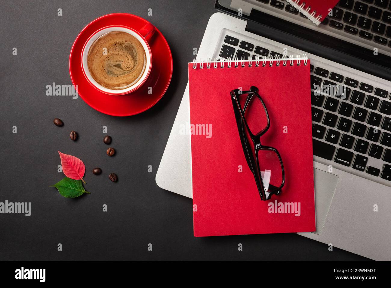 Tavolo da ufficio nero con computer portatile a schermo vuoto, notebook, tazza di caffè e altro ufficio. Vista superiore con spazio di copia. Foto Stock