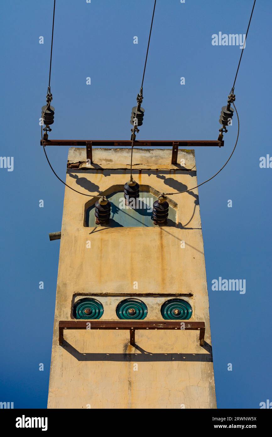 Torre in mattoni sulla strada con vecchi impianti elettrici e cavi elettrici Foto Stock